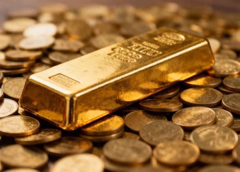 Barres d'or et pièces d'or scintillant sous la lumière.