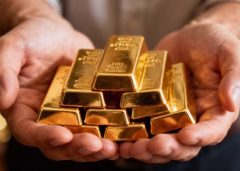 Mains tenant des lingots d'or brillants.