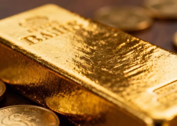 Lingot d'or brillant avec des pièces d'or éparpillées autour.