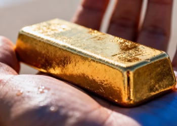 Main d'une personne tenant une barre d'or brillante.