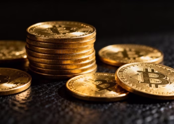 Pièces d'or d'investissement brillantes empilées et dispersées.