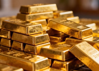 Lingots d'or empilés, reflétant la lumière.