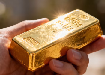 Main d'une personne tenant une barre d'or brillante.