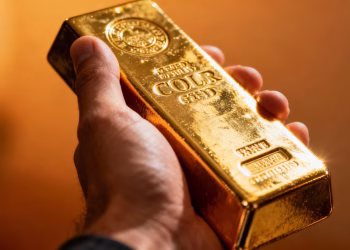 Main d'une personne tenant une barre d'or brillante.