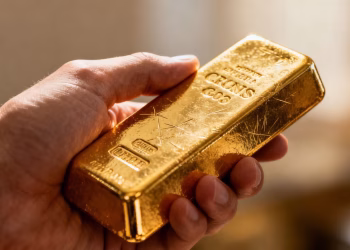 Main d'une personne tenant une barre d'or brillante.