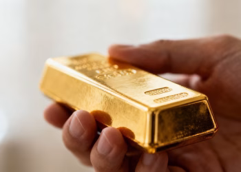 Main d'or tenant une barre d'or brillante.