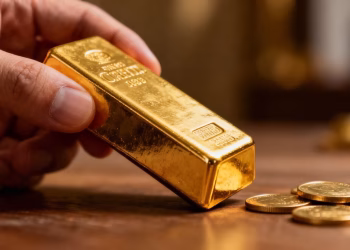 Main d'or tenant une barre d'or brillant.