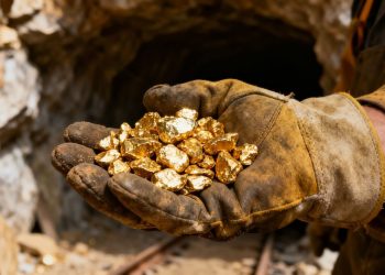 Main d'or tenant des pépites d'or dans une mine.