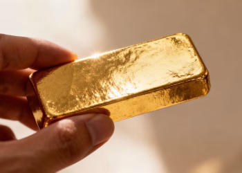 Personne tenant une barre d'or brillante.