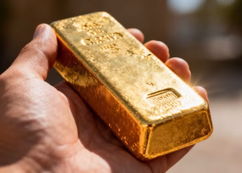 Main d'un professionnel tenant une barre d'or.