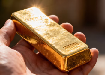 Main d'or tenant une barre d'or brillante
