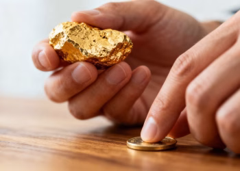 Main d'or tenant une pépite d'or et une pièce.