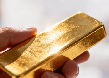 Main d'or tenant une barre d'or brillante.