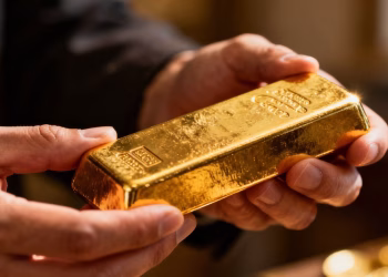 Mains tenant une barre d'or brillante.