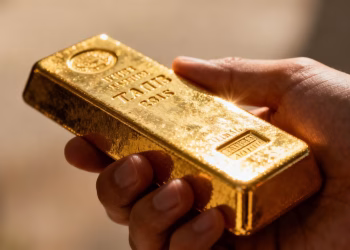 Main d'or tenant une barre d'or brillante.