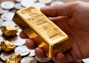 Main d'investisseur tenant une barre d'or brillante.