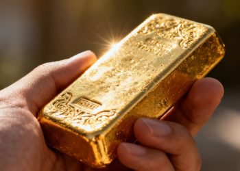 Main d'or tenant une barre d'or brillant.