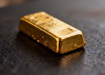 Lingot d'or posé sur une surface sombre.