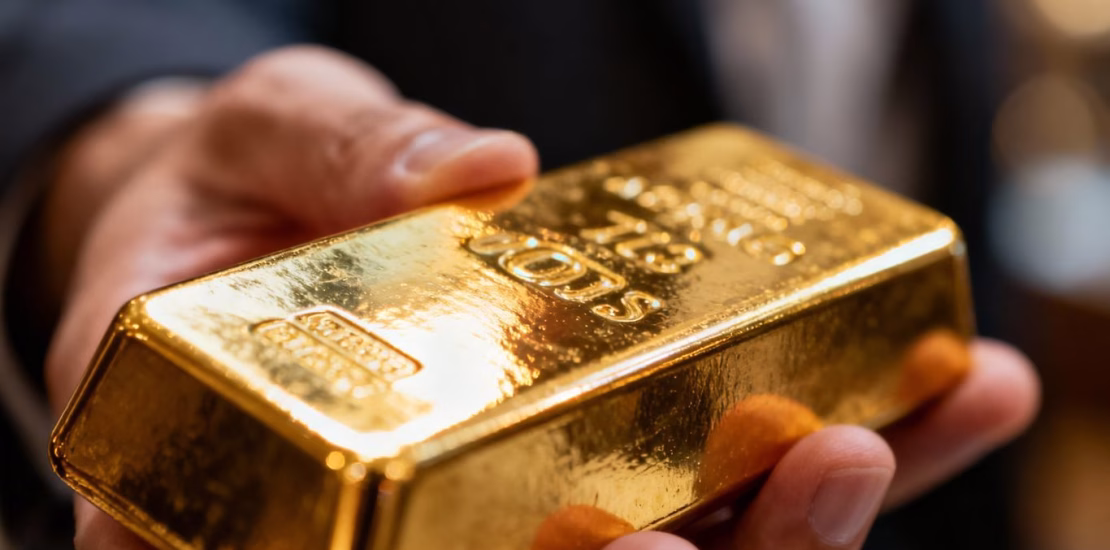 Personne tenant une barre d'or brillante.