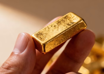 Main d'une personne tenant une petite barre d'or.