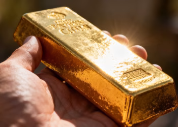 Main d'or tenant une barre d'or brillante.