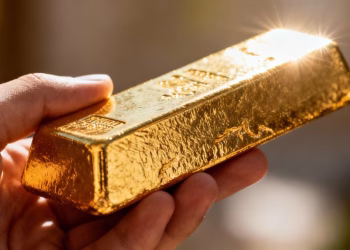Lingot d'or brillant tenu dans une main.