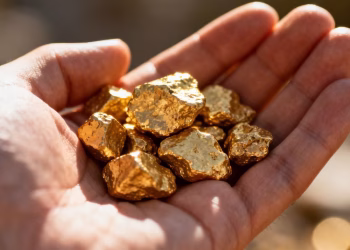 Main d'or tenant des pépites d'or brillantes.