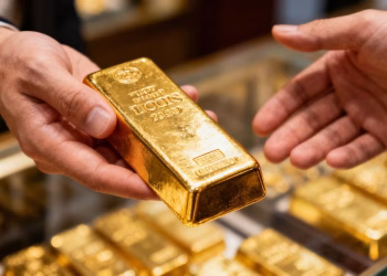Main tenant une barre d'or brillante.