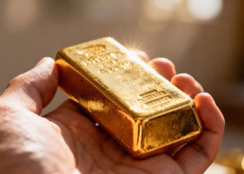 Main d'or tenant une barre d'or brillante