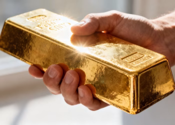 Main d'or tenant une barre d'or brillante.