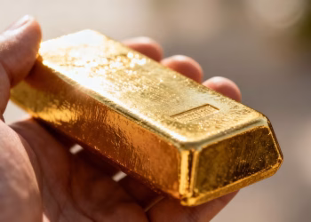 Main d'or tenant une barre d'or brillante.