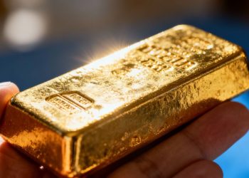 Main d'investisseur tenant une barre d'or brillante.