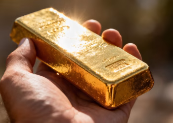 Barre d'or brillant tenue dans une main.