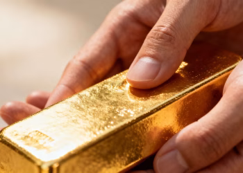 Main de personne tenant une barre d'or