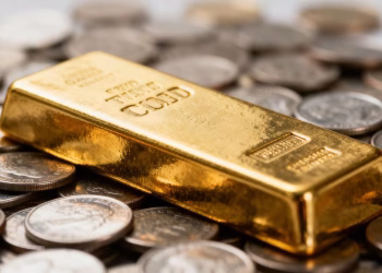 Barre d'or sur des pièces de monnaie éparpillées.