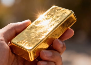 Main d'un homme tenant une barre d'or.