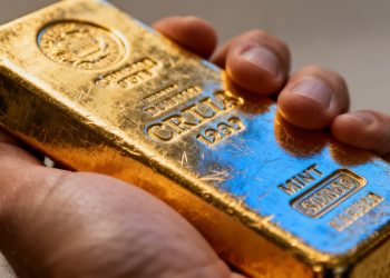 Une main tenant une barre d'or brillante.