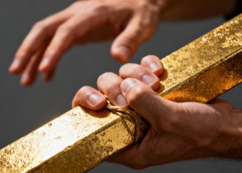 Main d'homme tenant une barre d'or brillant.