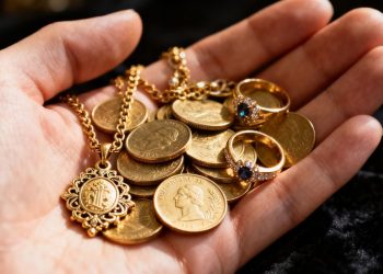 Main d'or tenant des pièces d'or et des bijoux.