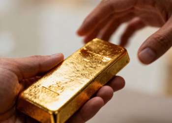 Mains tenant une barre d'or brillante, comparaison d'assurances.