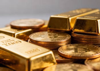 Lingots et pièces d'or brillants sur fond flou.