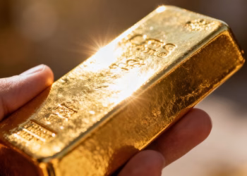 Une main tenant une barre d'or brillante.