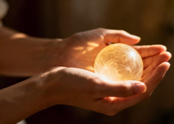 Mains protégeant une orbe lumineuse fragile.