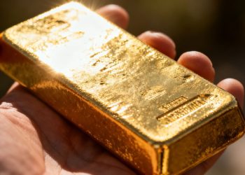 Main dorée tenant une barre d'or brillante.