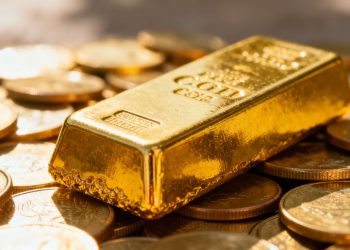 Lingots d'or et pièces d'or brillants sous la lumière.