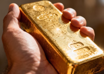 Main d'or tenant une barre d'or brillante.