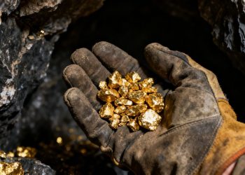Main d'ouvrier tenant des pépites d'or dans une mine.