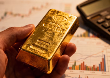 Main d'or tenant une barre d'or, arrière-plan financier flou.