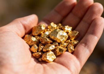 Main d'or tenant des pépites d'or brillantes.