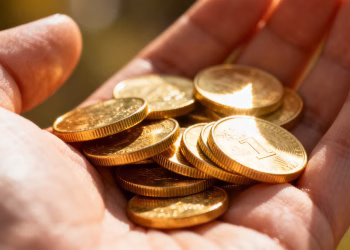 Main dorée tenant des pièces d'or brillantes.